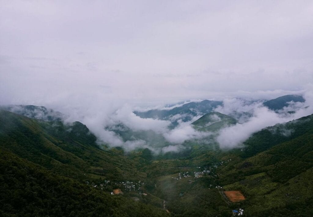 Clouds shroud a lush, green mountain landscape.-Baliem Valley Indonesia
