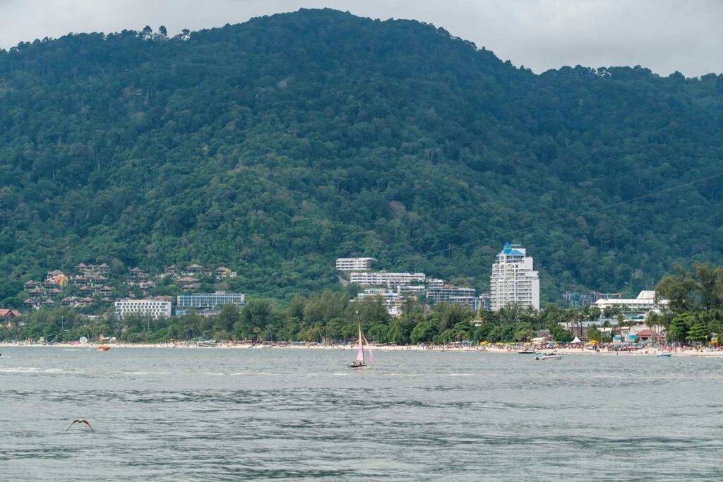A beach, buildings, and a lush green mountain.-Koh Mak Thailand