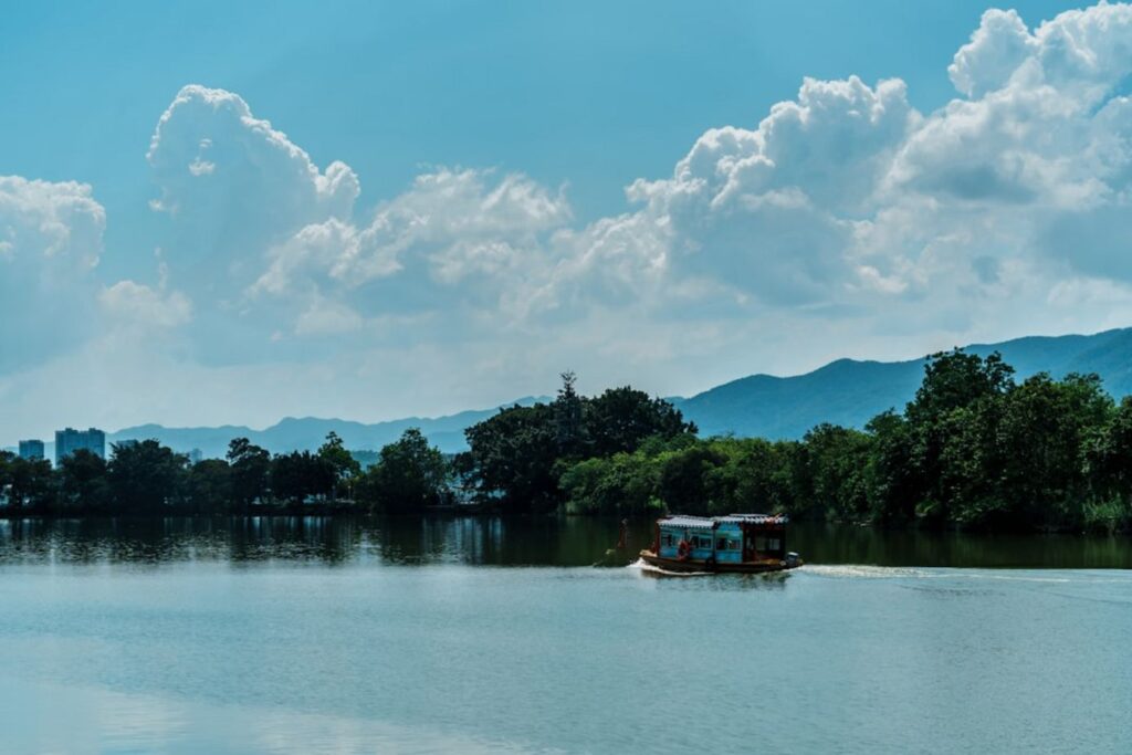 A boat floats on a calm lake under a cloudy sky.-Nong Khai Thailand