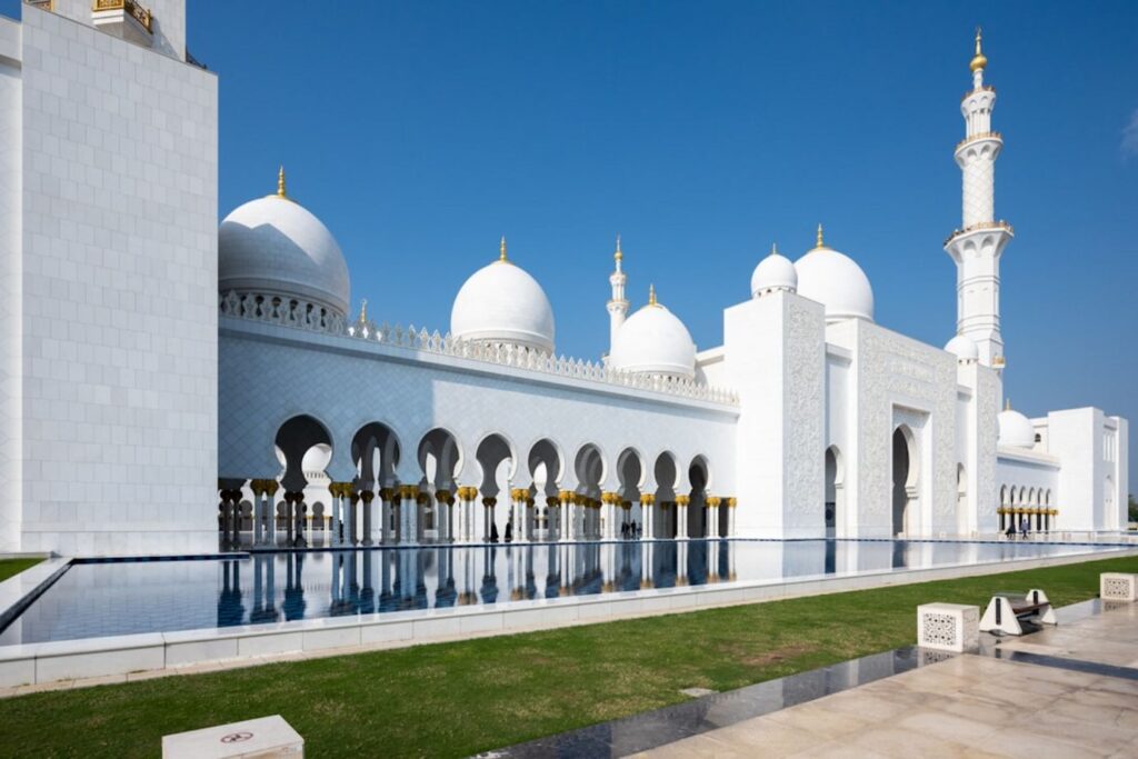 A grand white mosque with a tall minaret under blue sky-Fujairah United Arab Emirates