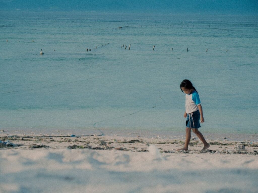 A child walks along a sandy beach by the ocean.-Maldives traffic