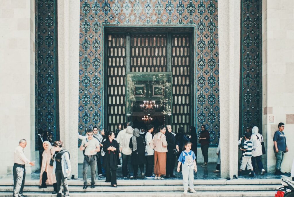 People gather at the entrance of a grand building.-Fahaheel Kuwait
