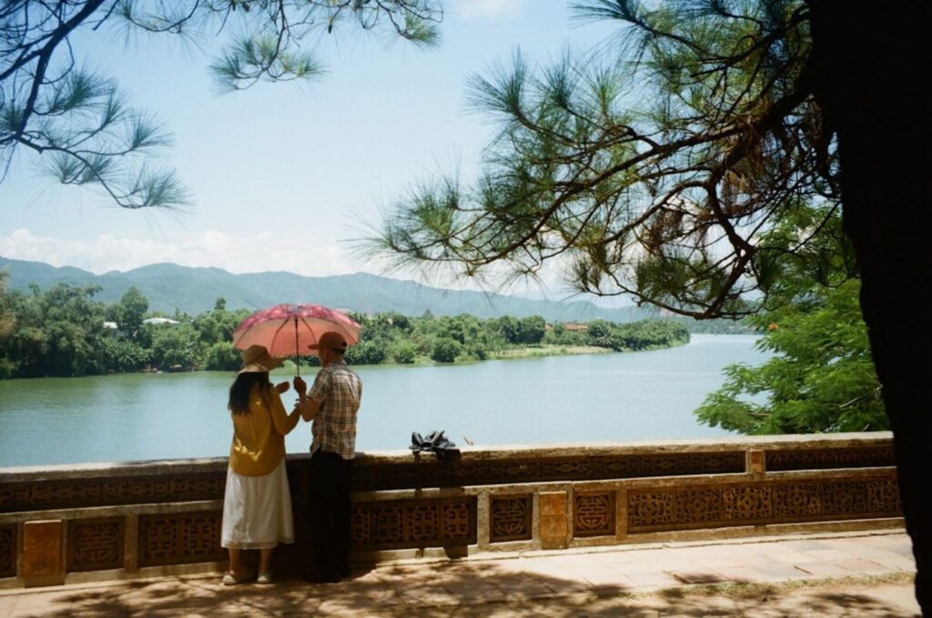 Two people with umbrella by river and trees-cambodia tourists
