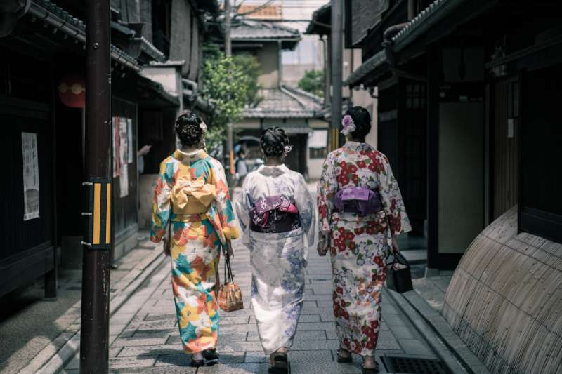 Three Geisha Walking Between Buildings