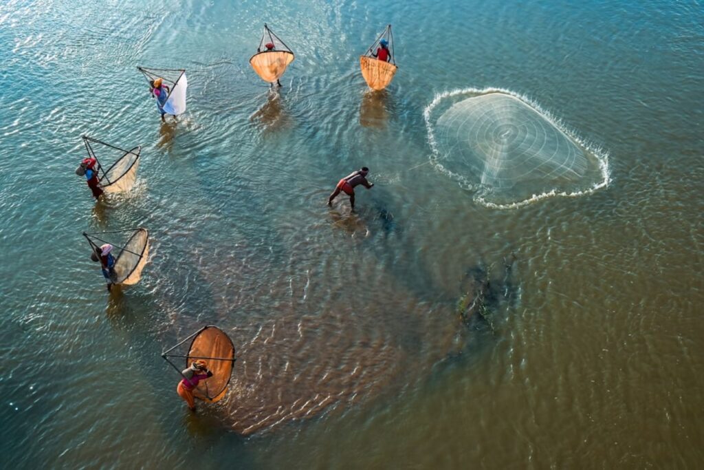 Fishermen casting nets in a body of water.-malaysia snorkeling