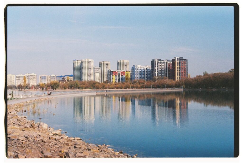 Modern buildings reflected in a calm lake during autumn.-Kazakhstan vulcano