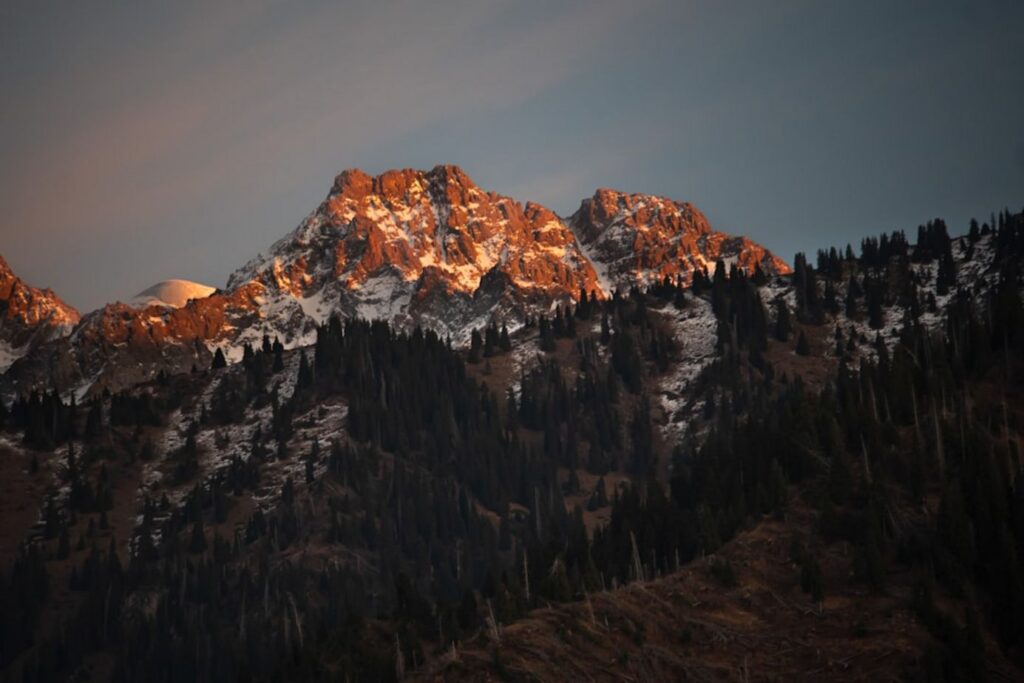 Golden sunlight illuminates snow-capped mountain peaks at sunset-Kazakhstan mountain
