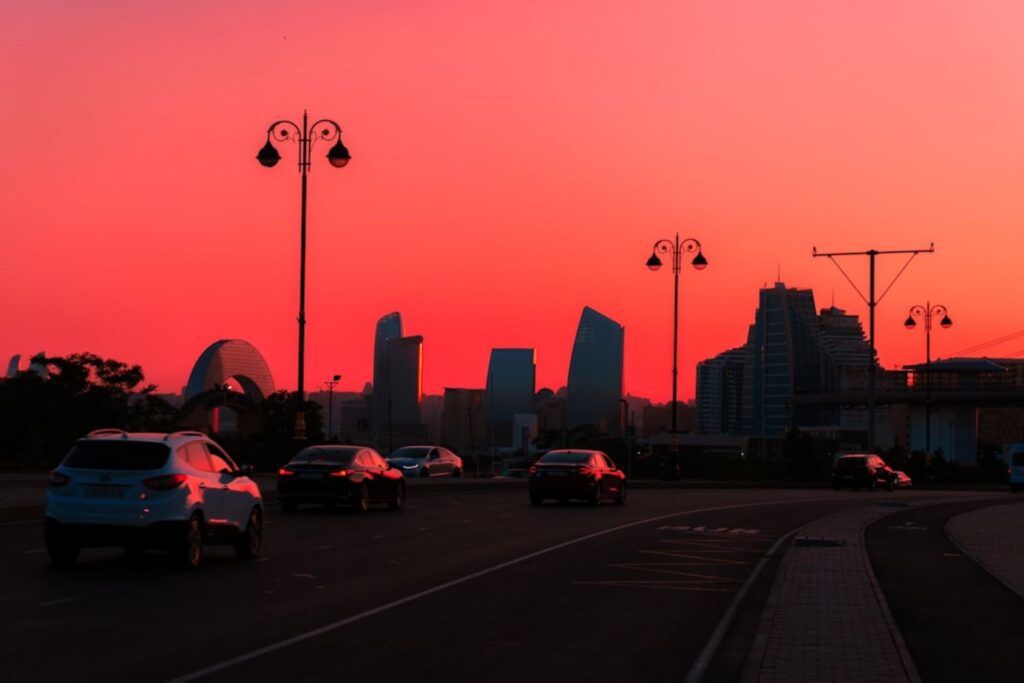 Cars driving on road with city skyline at sunset.-Azerbaijan