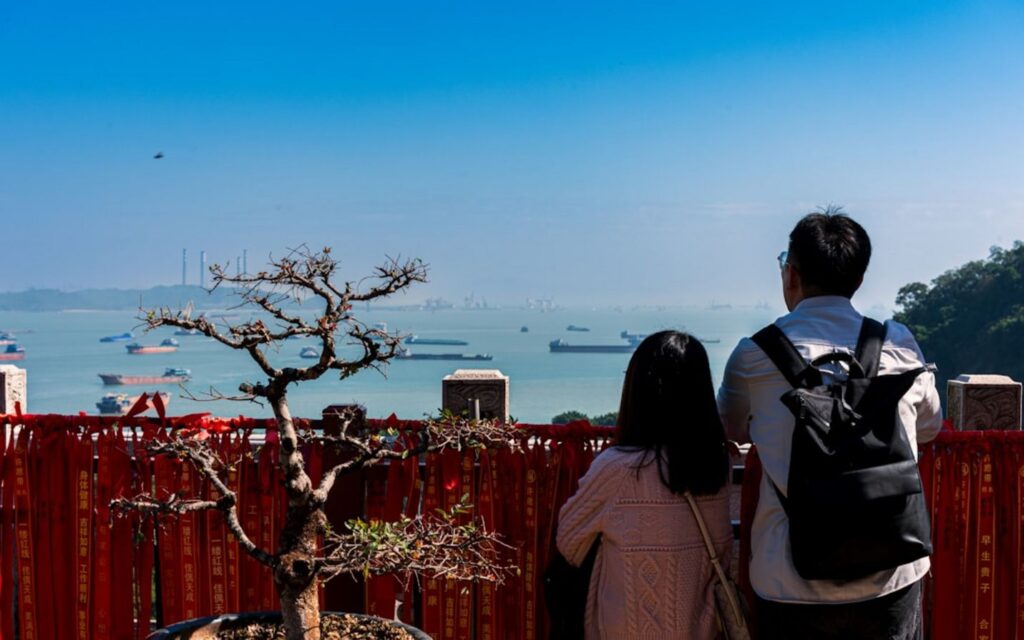Two people look at ships in a harbor.-sanya China